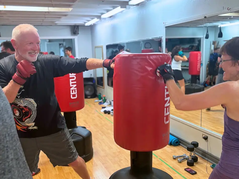 Adult students in a kickboxing class punching standing bags