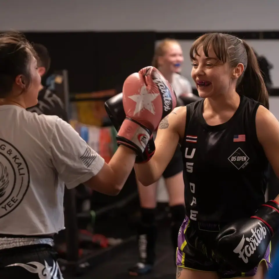 Two women training Muay Thai pad work together at The Martial Club
