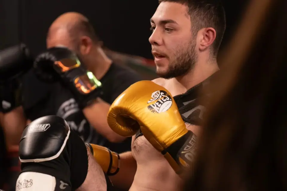 A Muay Thai student in gold gloves throwing a strike during class at The Martial Club